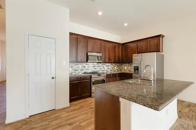 a kitchen with kitchen island granite countertop a stove sink and refrigerator