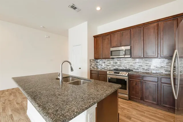 a kitchen with kitchen island granite countertop a sink stove and cabinets