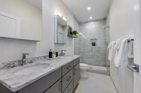 a bathroom with a granite countertop sink a toilet and shower