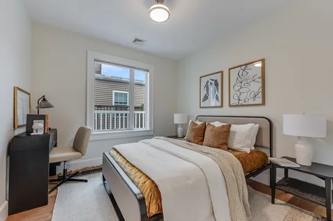 a bedroom with a bed and a window with chair