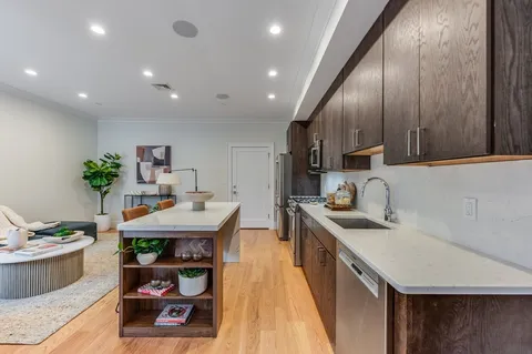 a kitchen with stainless steel appliances kitchen island granite countertop a sink a stove and a wooden floors