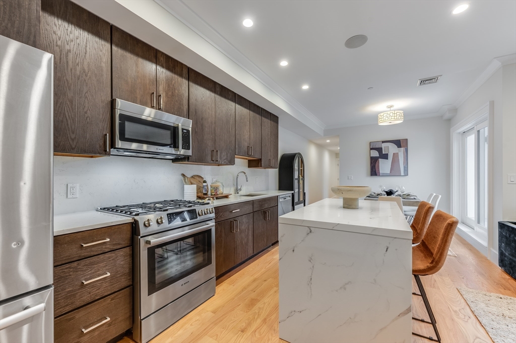 17 Vinton Street, Unit 3 Boston, MA 02127 - Photo 3 of 21 a large kitchen with stainless steel appliances granite countertop a stove top oven a sink dishwasher and a refrigerator with wooden floor