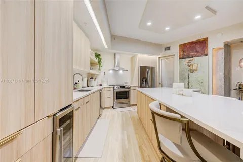 a large white kitchen with stainless steel appliances granite countertop lots of counter top space and a sink