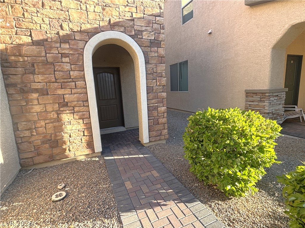 121 Elm Reed Avenue Las Vegas, NV 89113 - Photo 3 of 30 An inviting stone archway frames the entrance to this charming residence, enhanced by mature landscaping.