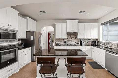 a kitchen with stainless steel appliances a stove a sink a stove a microwave a refrigerator cabinets and a refrigerator