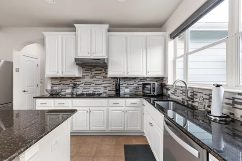 a kitchen with stainless steel appliances granite countertop a sink stove and cabinets