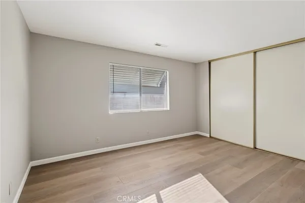 an empty room with wooden floor closet and windows