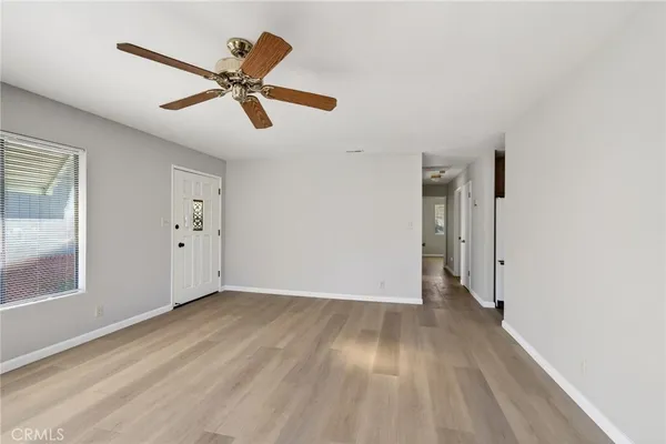 a view of an empty room with wooden floor and a window