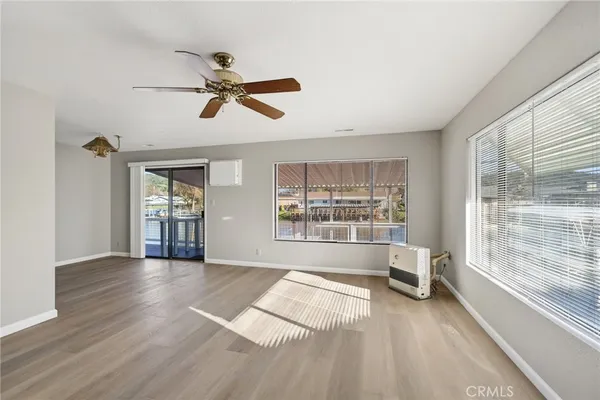 a view of an empty room with a window and wooden floor