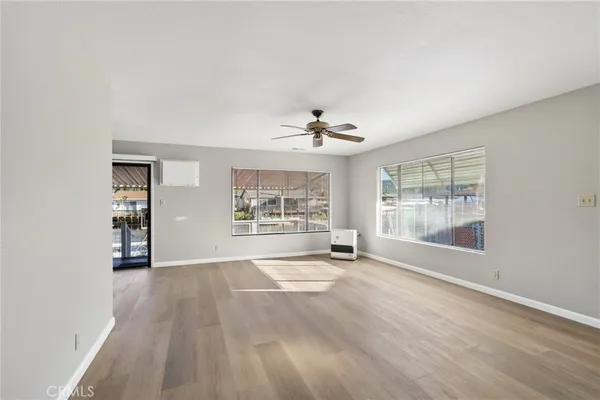a view of an empty room with a window and wooden floor