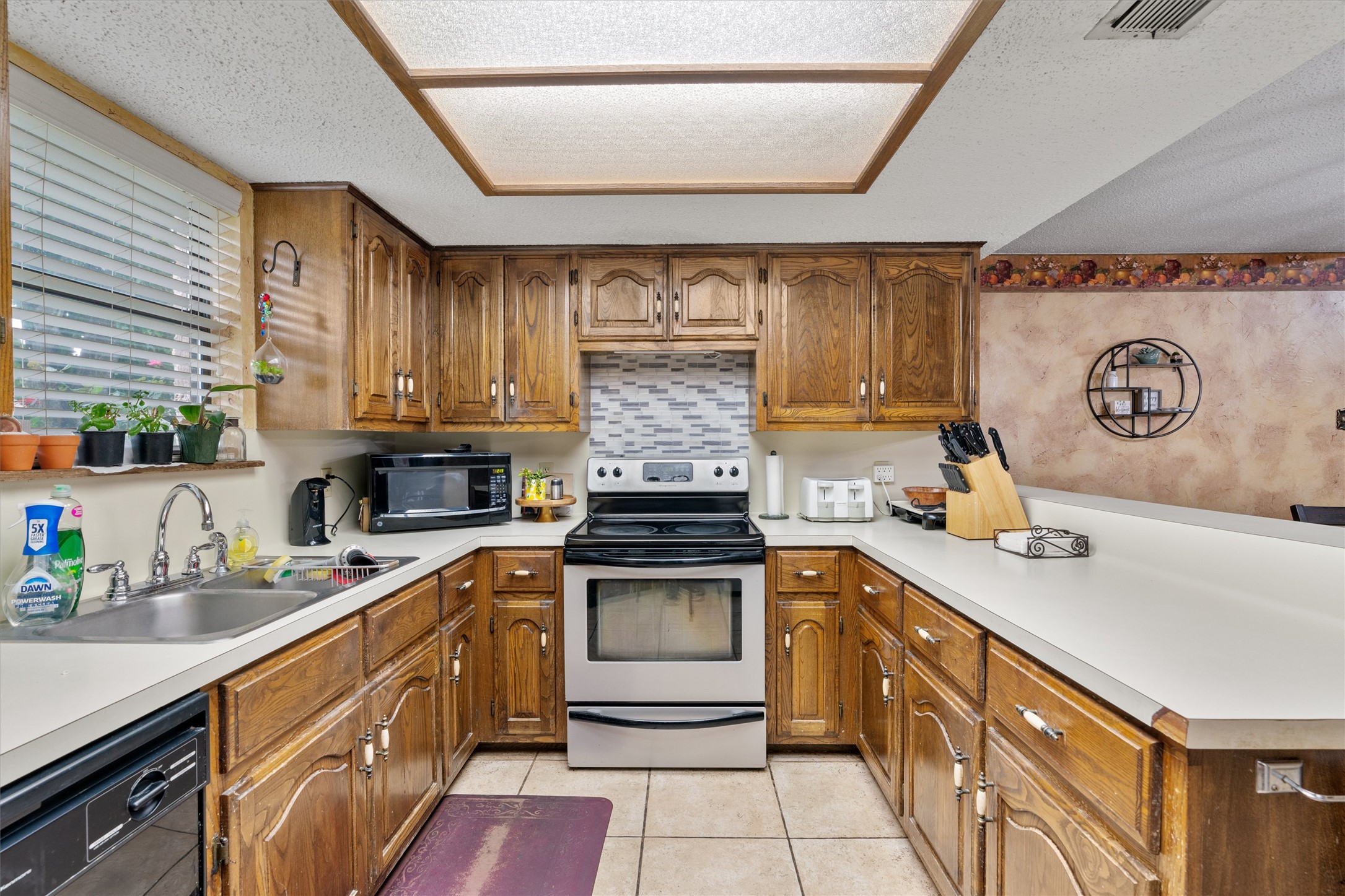 401 Drake Lane Taylor, TX 76574 - Photo 11 of 31 U-shaped kitchen featuring wood cabinetry, light-toned countertops, and a tile backsplash
