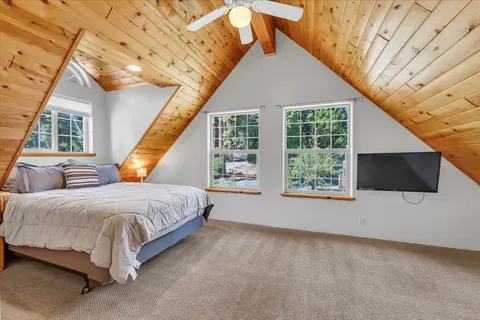 a spacious bedroom with a bed a flat screen tv and balcony