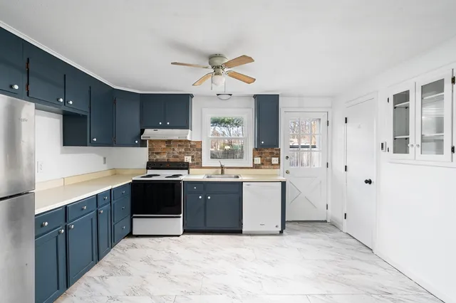 a kitchen with stainless steel appliances a sink a stove a refrigerator cabinets and a window