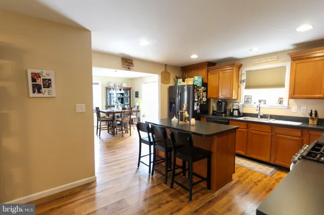 a kitchen with stainless steel appliances granite countertop a table chairs sink and wooden floor