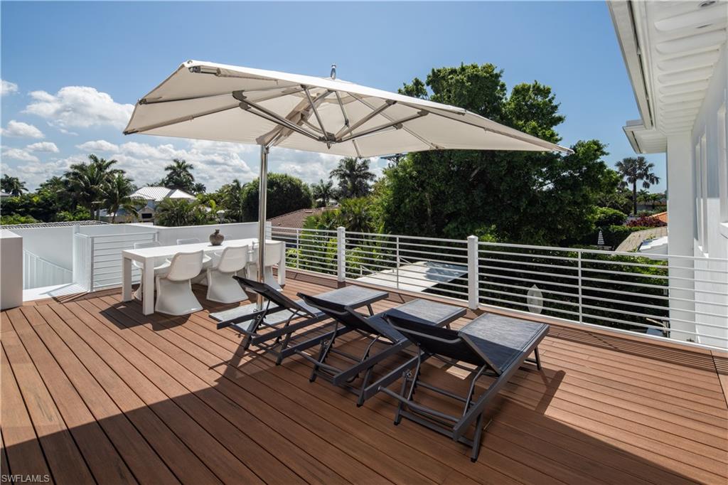 3770 Crayton Road Naples, FL 34103 - Photo 16 of 26 a view of a roof deck with table and chairs under an umbrella