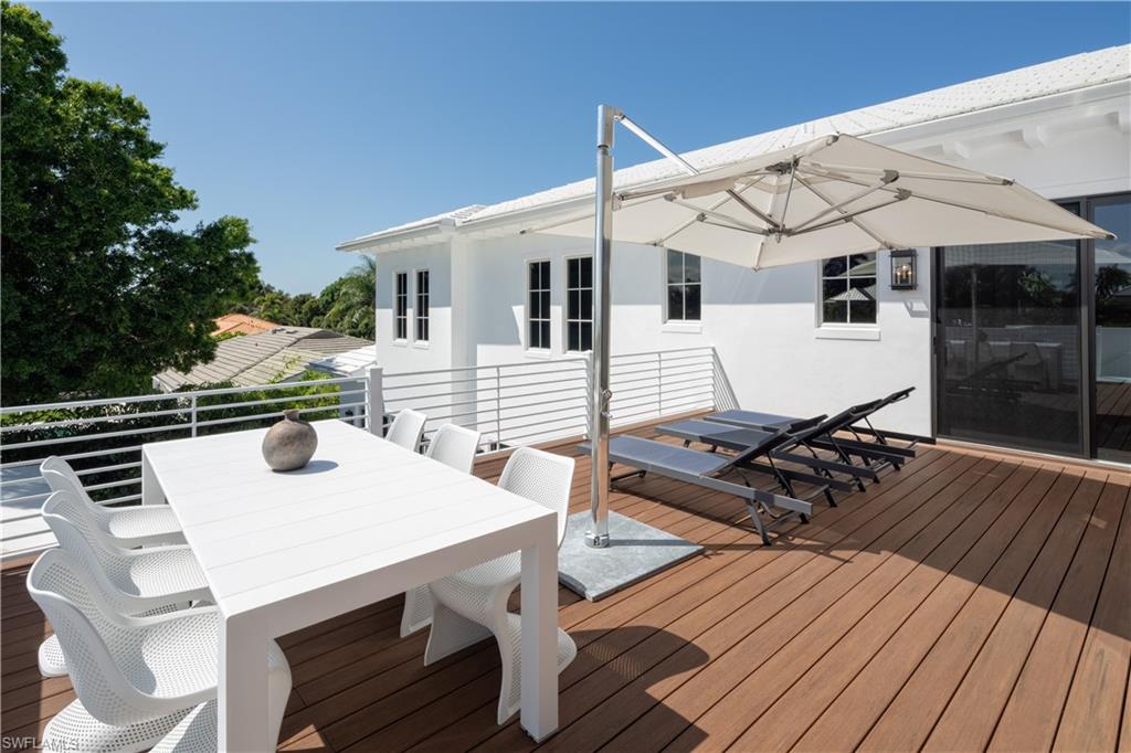 3770 Crayton Road Naples, FL 34103 - Photo 17 of 26 a view of a deck with table and chairs with wooden floor and fence