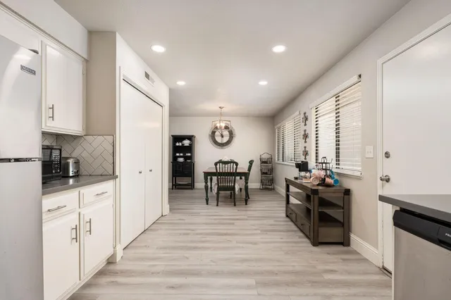a large white kitchen with wooden floor and stainless steel appliances