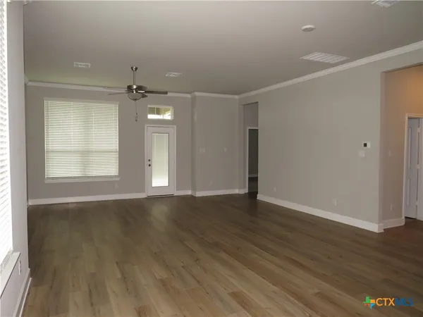 an empty room with wooden floor and windows