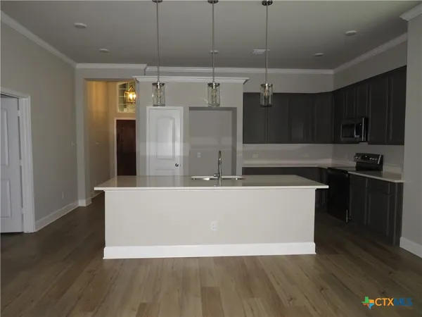 a living room with stainless steel appliances kitchen island granite countertop a refrigerator a stove and a wooden floors