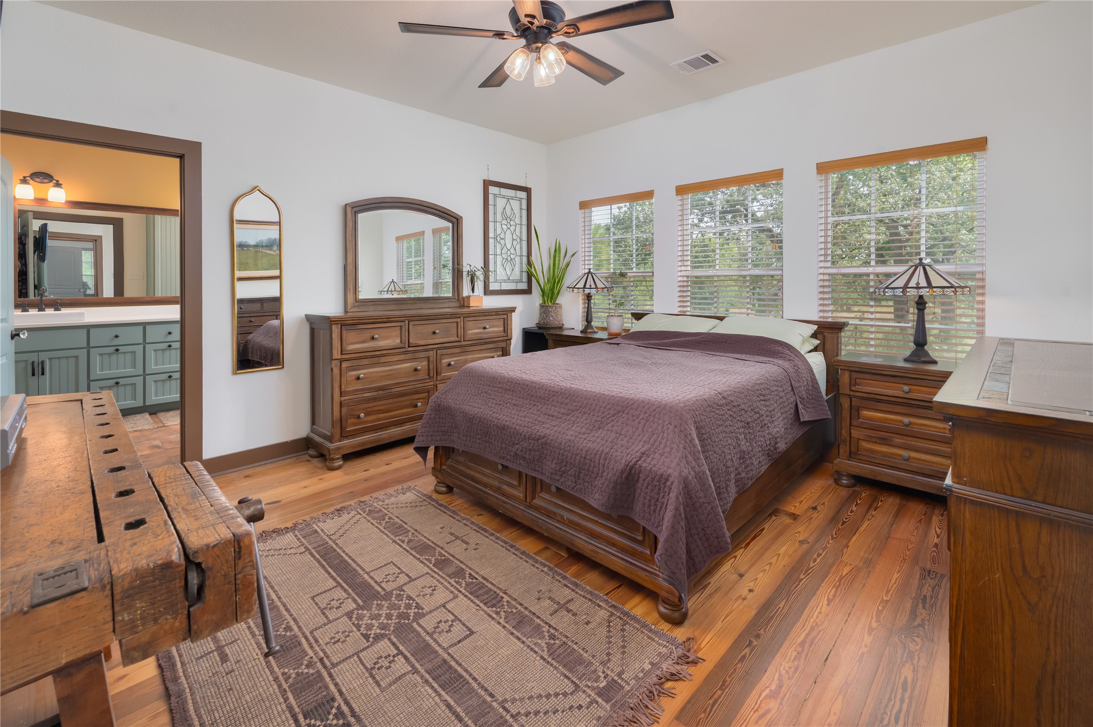 270 Dry Creek Road Manor, TX 78653 - Photo 9 of 40 Well-lit sleeping quarters with natural wood flooring and ample windows overlooking green surroundings.
