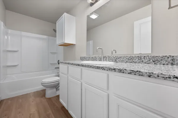 a bathroom with a granite countertop toilet sink and mirror
