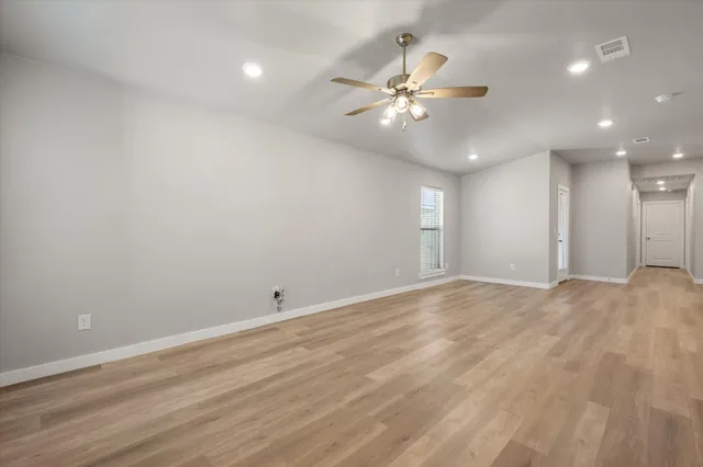 an empty room with wooden floor and fan