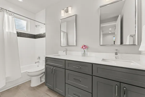 a bathroom with a double vanity sink toilet mirror and bathtub