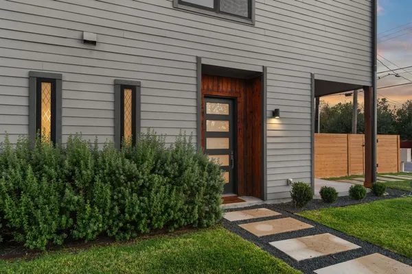 a view of a house with brick walls and a yard with plants
