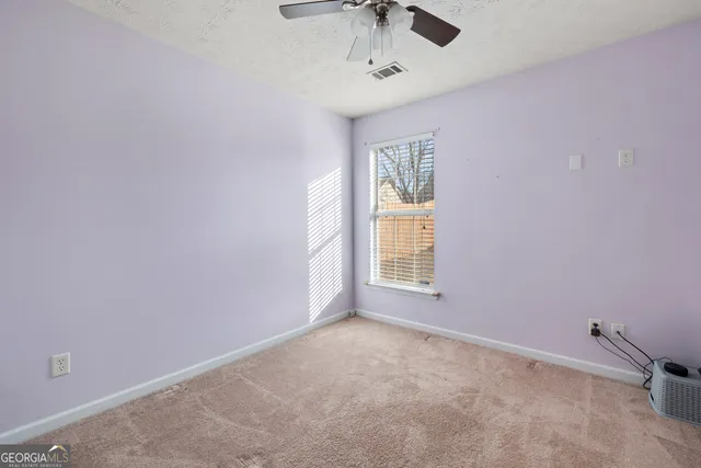 an empty room with windows and fan