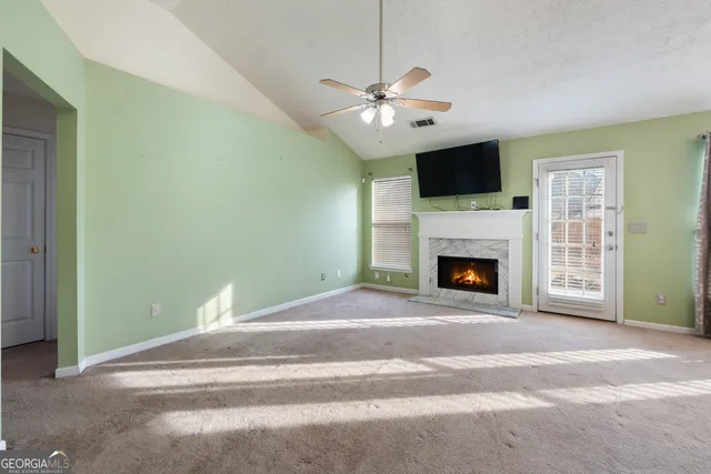 a view of a livingroom with a fireplace a ceiling fan and a rug