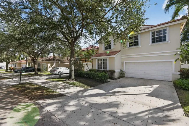a view of a white house with a large tree