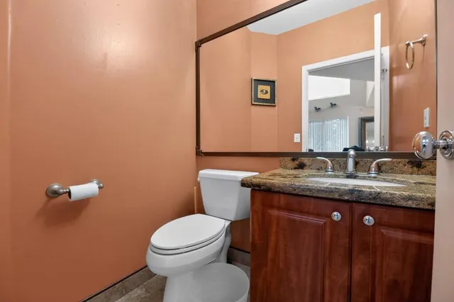 a bathroom with a granite countertop sink a toilet and a mirror