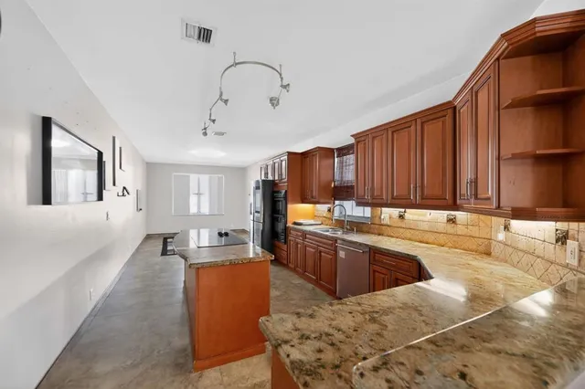 a large kitchen with kitchen island a large counter top space a sink a window and stainless steel appliances