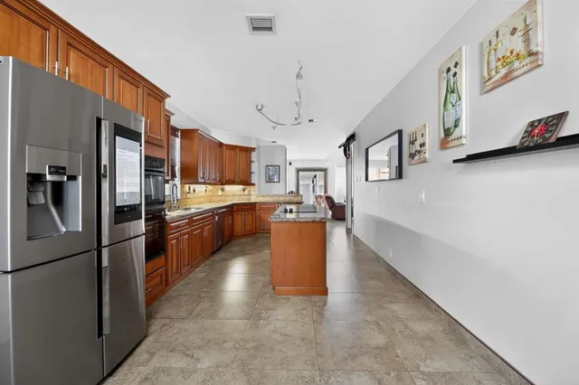 a large kitchen with stainless steel appliances granite countertop a refrigerator a oven a sink and a stove