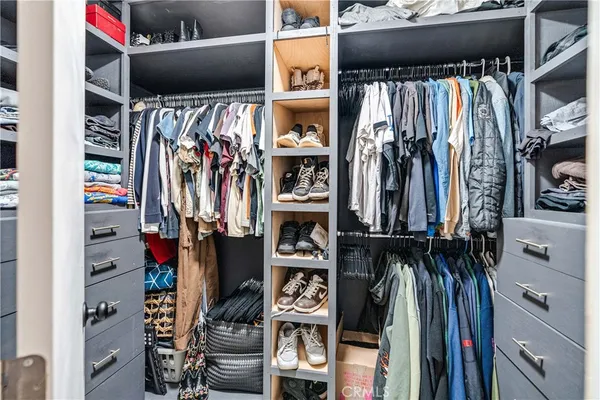 a view of walk in closet with clothes and shoes