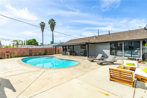 a blue swimming pool with outdoor seating and plants