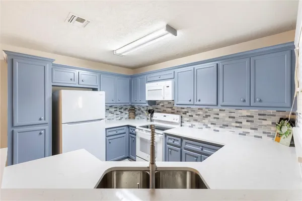 a kitchen with a sink a refrigerator and cabinets