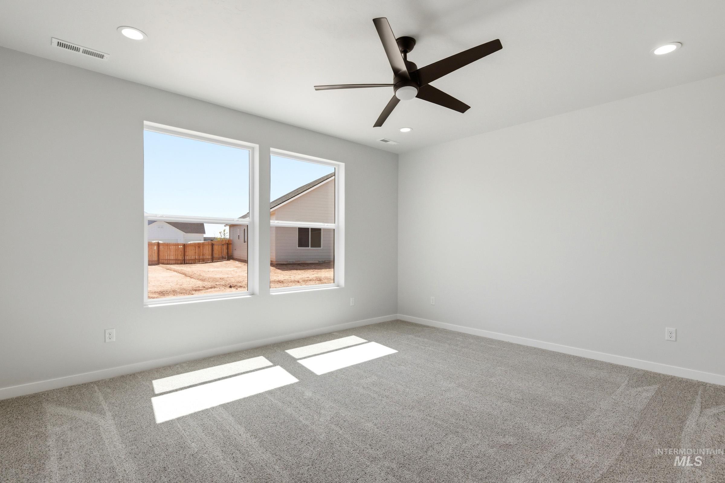 13649 Inman Court Caldwell, ID 83607 - Photo 19 of 22 Spacious room featuring two large windows, light gray walls, and matching carpeting