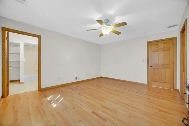 a view of empty room with wooden floor and ceiling fan