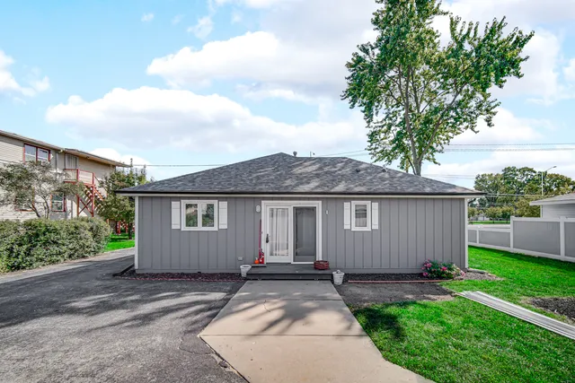 front view of house with a yard and trees all around