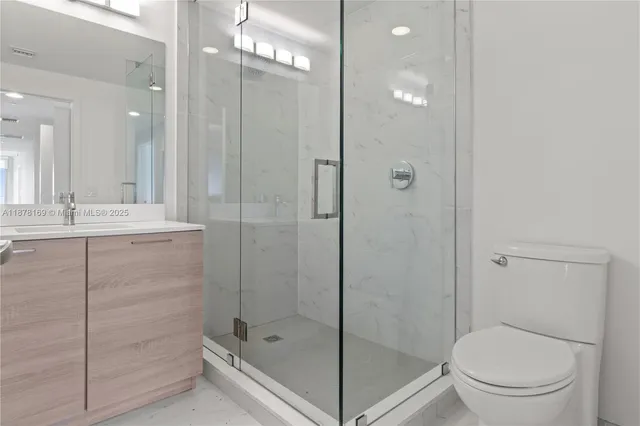 a bathroom with a shower sink mirror and toilet