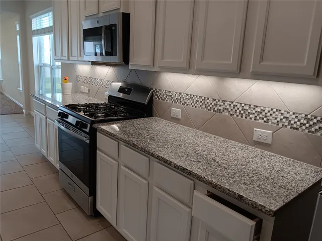 a kitchen with granite countertop white cabinets and stainless steel appliances