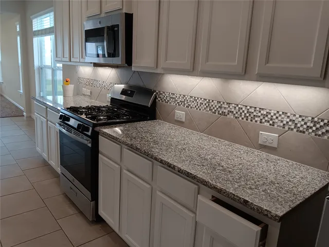 a kitchen with granite countertop white cabinets and stainless steel appliances
