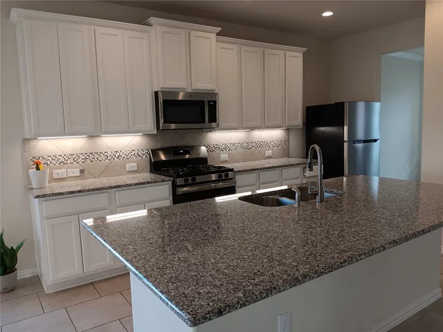 a kitchen with granite countertop a sink a stove and a microwave