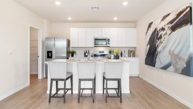 a kitchen with stainless steel appliances granite countertop a table chairs refrigerator and microwave