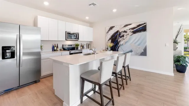 a kitchen with stainless steel appliances a table chairs refrigerator and microwave