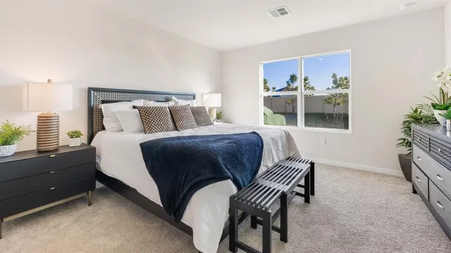 a bedroom with a bed and a potted plant on the dresser