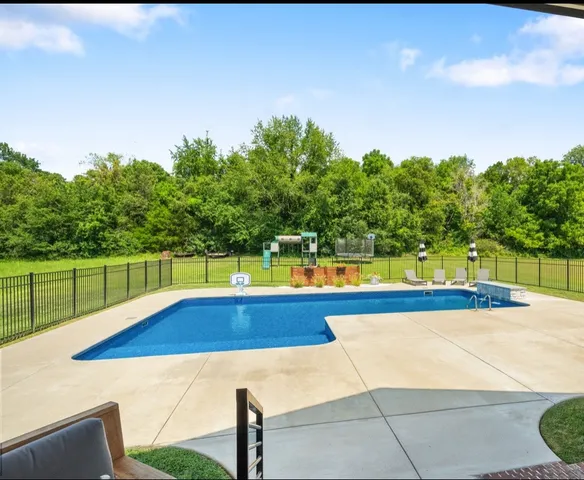 a view of swimming pool with seating area and trees in the background