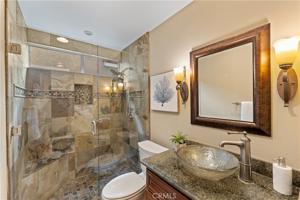 2741 Timmons Tustin, CA 92782 - Photo 13 of 30 a bathroom with a granite countertop sink toilet a mirror and shower