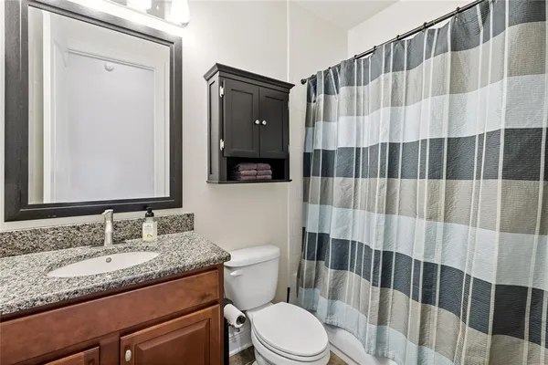 a bathroom with a granite countertop sink toilet and shower